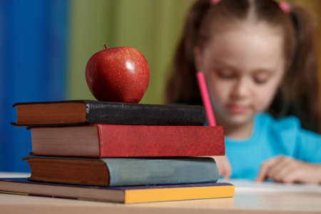 Little girl writing something in copybook and sitting at table.の写真素材