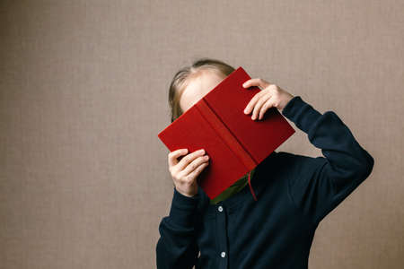 Beautiful baby covering her face with a book. Back to school.の写真素材