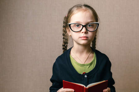 Back to school. little girl in glasses with bookの写真素材