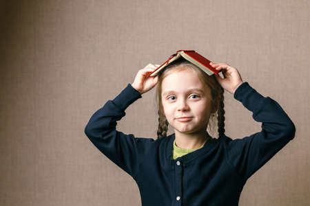 young girl with a book on her head. Back to school.