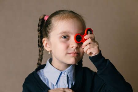 Little caucasian school girl with Fidget Spinner held up to his eyesの写真素材