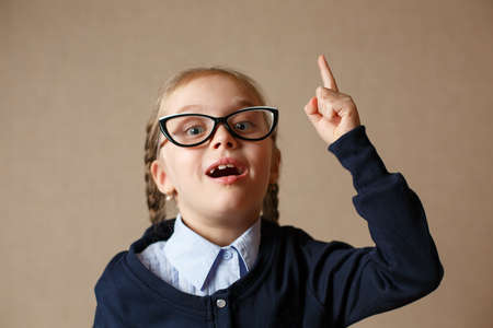 A little girl with glasses raised her finger up. Concept of the ideaの写真素材