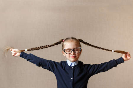Cute small girl in glasses pulling her hairの写真素材