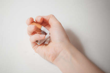 Close-up hand crushing a pile of cigarettes. Angry hand breaking tobacco. Gesture for anti, quit smoking addiction concept. Stop smoking message, social issue concept background.の写真素材