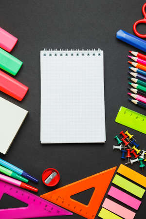 Colorful school supplies on dark stone board, background with copy space. Selective focus. Vertical...