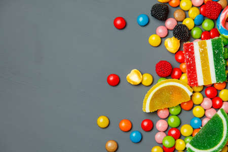 Colorful candies and lollipops over stone background. Top view with copy spaceの写真素材