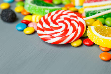 Mixed colorful fruit bonbon on gray wooden background