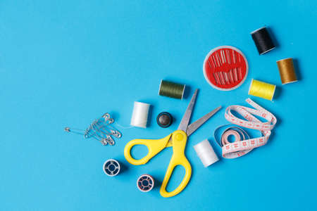 Tailoring Accessory Flatlay on Neutral Background. Top View of Spools of Thread, Bobbin, Pins and Neddle. Yellow Scissors and Measuring Tape. Dressmaking Tackle Item for Clothes Designの写真素材