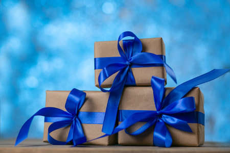 Christmas gift boxes with blue ribbons against blue lights garland and bokeh background. Holiday...