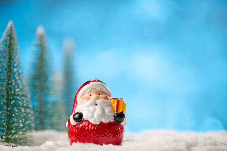 Toy Santa Claus and Christmas trees on abstract light blue background with copy space.の写真素材