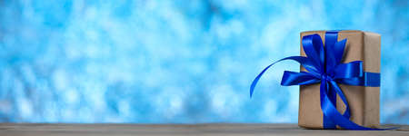 Gift box with a ribbon bow on the desk on blue abstract background