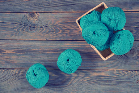 Wool yarn on a wooden table and in basket. Composition of wool balls:, wooden basket. Home comfort,...