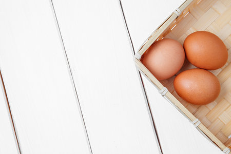Three brown eggs in basket on a wooden background. top view. horizontal shoot