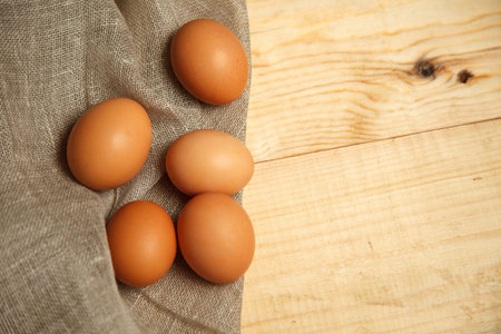 Fresh chicken brown eggs on linen napkin at rustic wood table. Rural still life, natural healthy...