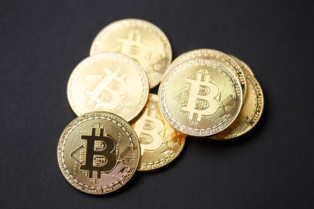 Many gold bitcoins with a single bitcoin in sharp focus floating above them to illustrate bitcoin exchange, mining or blockchain technology for cryptocurrencyの写真素材