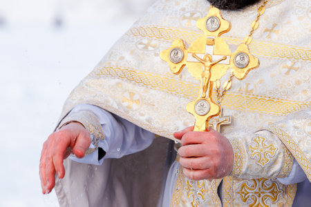 Gold cross in the hands of a priest close-up. Time to consecrate the water.の写真素材