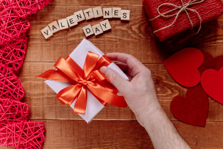 A gift with a red ribbon for Valentine's Day in your hands. The view from the top.の写真素材