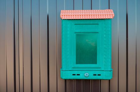 Traditional mailbox which is hanging on a metal fence.