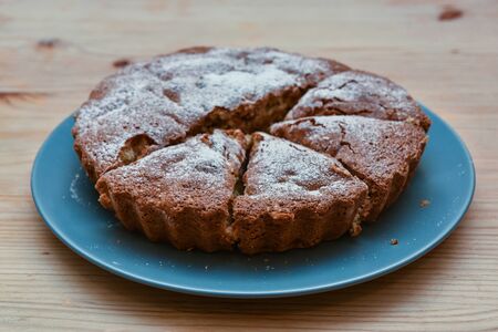 homemade cake sprinkled with icing sugar on a plate on a wooden table.の写真素材