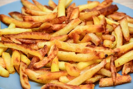closeup french fries on a blue plate on a wooden background.の写真素材