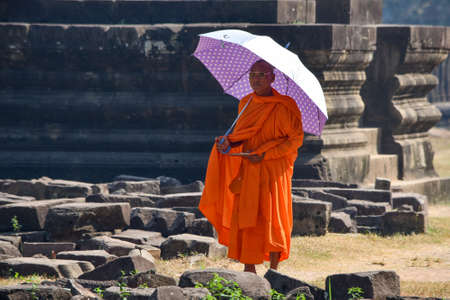 Siem Reap, Cambodia - 15 January 2019 - Buddhist monk walking around Angkor Wat with a tablet and an umbrella.のeditorial素材