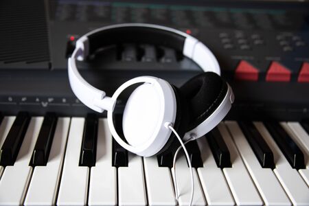 electronic piano or synthesizer with white headphones close-up. music devices.の写真素材