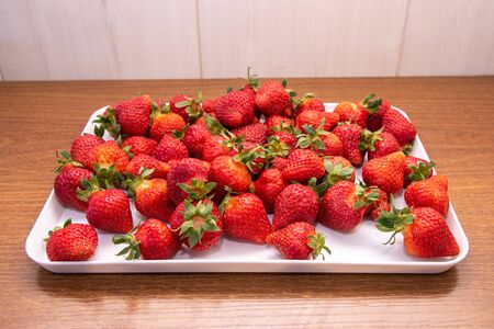 tasty strawberries in a white tray on a wooden background. Close-up.の写真素材