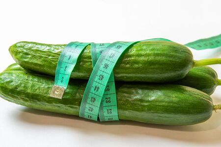 Three fresh cucumbers and measuring tape. Diet and Healthy life, loss weight concept. Isolated. White background.の写真素材