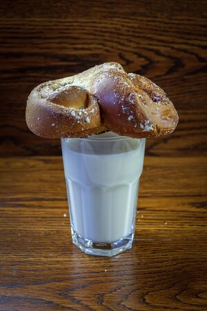 Fresh bun on a glass of milk on a wooden background close up with copy space.の写真素材