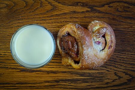 glass of milk and a bun on a wooden background close up with a copy of the space top view.の写真素材