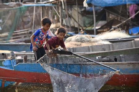 Siem Reap, Cambodia - 17 01 2019 - children pull fishing net out of Tonle Sap lake, the floating village.のeditorial素材