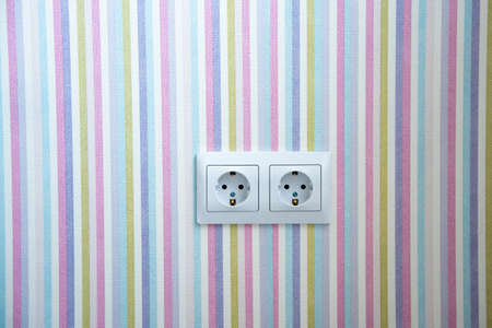 Two white Power sockets with frame on color wallpaper as a background.