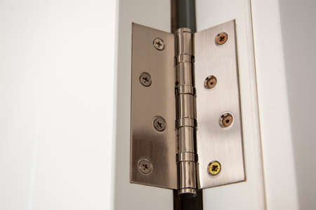 door hinges Aluminum on white door close up.