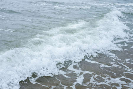 Small waves on the sea coast, foaming waves.