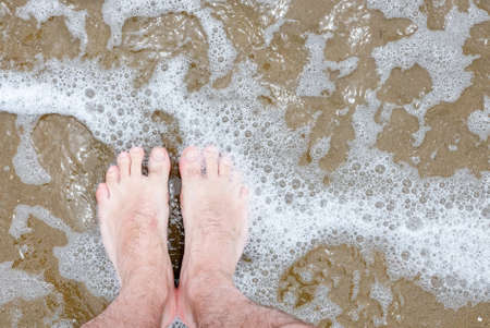 mans feet in water with waves lapping.の写真素材