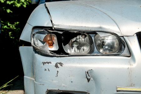 Close-up of a broken headlight on a gray car on a sunny day. Crash concept.の写真素材