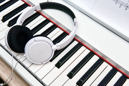 white headphones lie on the keyboard of the electronic piano.の写真素材