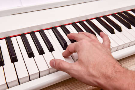 Close-up of the hand of a musical artist playing the piano, a man's hand, classical music, keyboard, synthesizer, pianist.の写真素材
