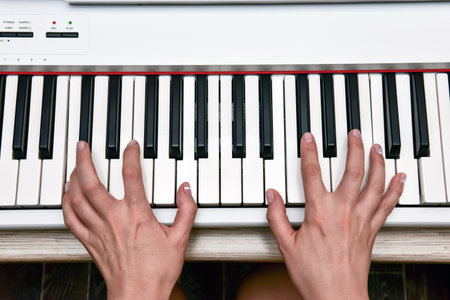 Woman's hands playing electronic digital piano at home. The woman is professional pianist arranging music using piano electronic keyboards. Musician practicing keyboard composing music.の写真素材