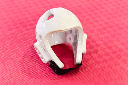 White Taekwondo head guard on a red training mat.の写真素材