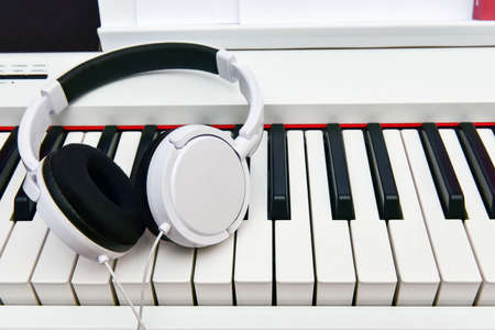 white headphones lie on the keyboard of the electronic piano.の写真素材