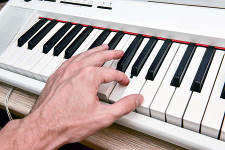 Close-up of the hand of a musical artist playing the piano, a man's hand, classical music, keyboard, synthesizer, pianist.の写真素材
