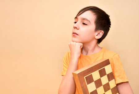 boy holds a chessboard in his hands and dreams and thinks about the game. free space for text.の写真素材