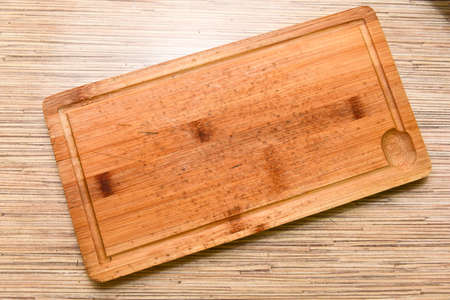 Old chopping board on wooden background top view.の写真素材