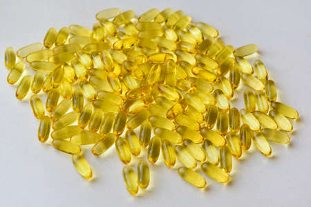 Bunch of omega 3 fish liver oil capsules in pile. Close up of big golden translucent pills texture. Healthy every day nutritional supplement. Top view.の写真素材