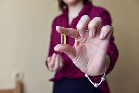 The woman in her hand holds a capsule of omega-3 fish oil. Medical healthcare, healthy food concept. Vitamin tablets.の写真素材