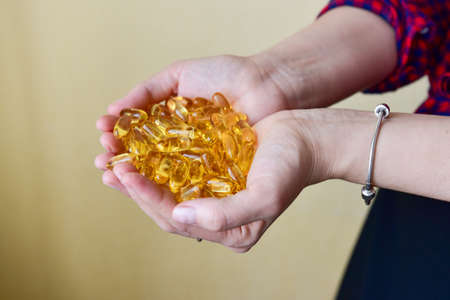 Hands holding fish oil Omega-3 capsules. Medical healthcare, healthy nutrition supplements concept. Vitamin tablets.の写真素材