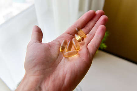 Hand holding fish oil Omega-3 capsules. Medical healthcare, healthy nutrition supplements concept. Vitamin tablets.の写真素材