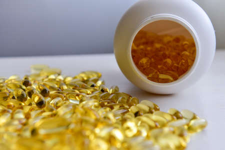 Fish oil capsules with omega 3 and vitamin D in a bottle on wooden texture, healthy diet concept, close up shot.の写真素材
