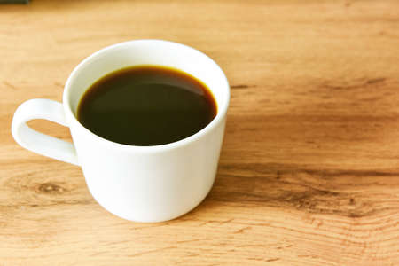 White cup of strong black coffee on wooden surface close up.の写真素材